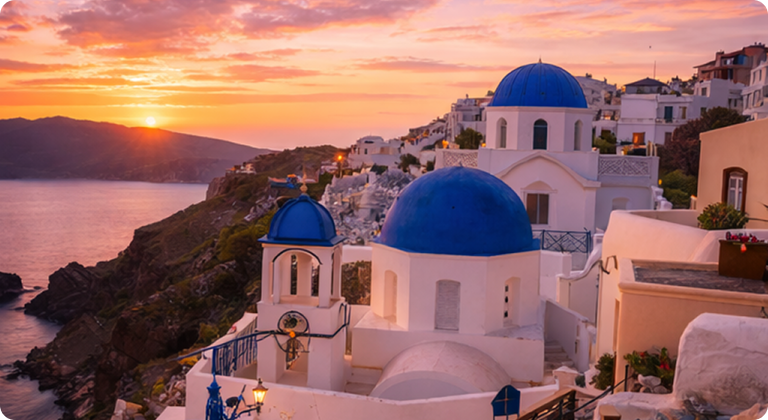 Santorini whitewashed buildings with blue domes at sunset overlooking Aegean Sea